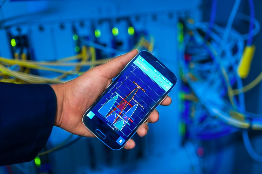 pexels-photo-19353800-19353800 Hand holding smartphone displaying network analysis in high-tech server environment.